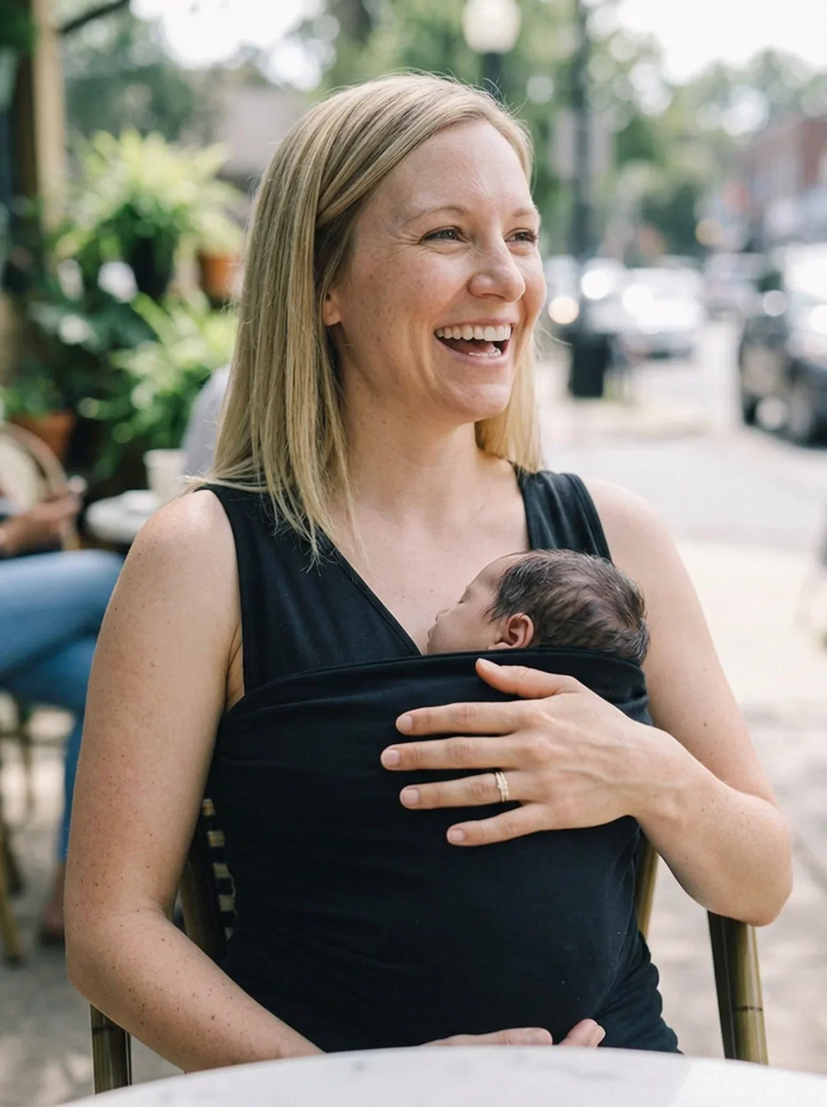 Débardeur porte-bébé Hugaya porté par une mère, bébé installé contre elle, coloris noir