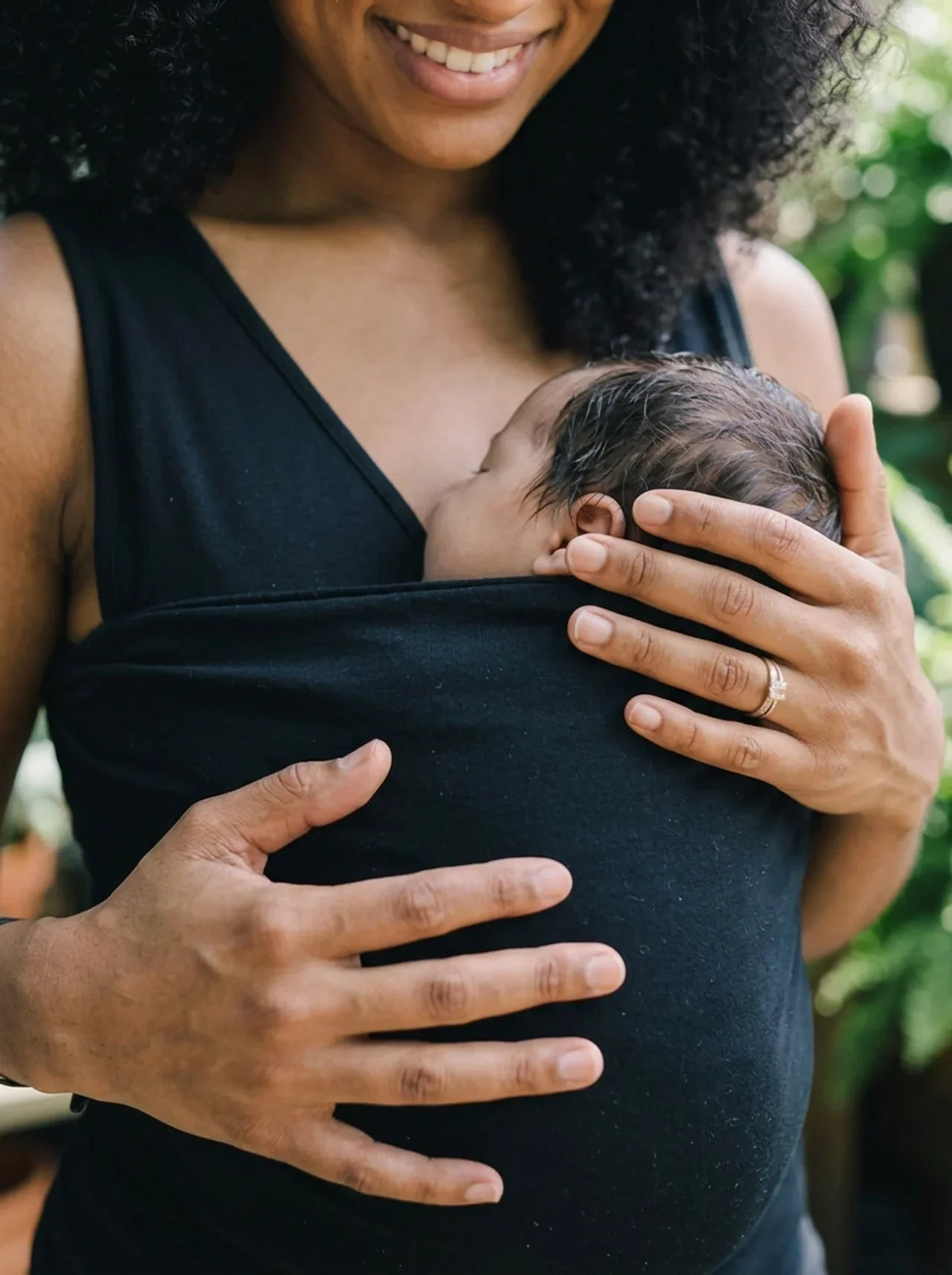 Débardeur porte-bébé Hugaya porté par une mère, bébé installé contre elle, coloris noir