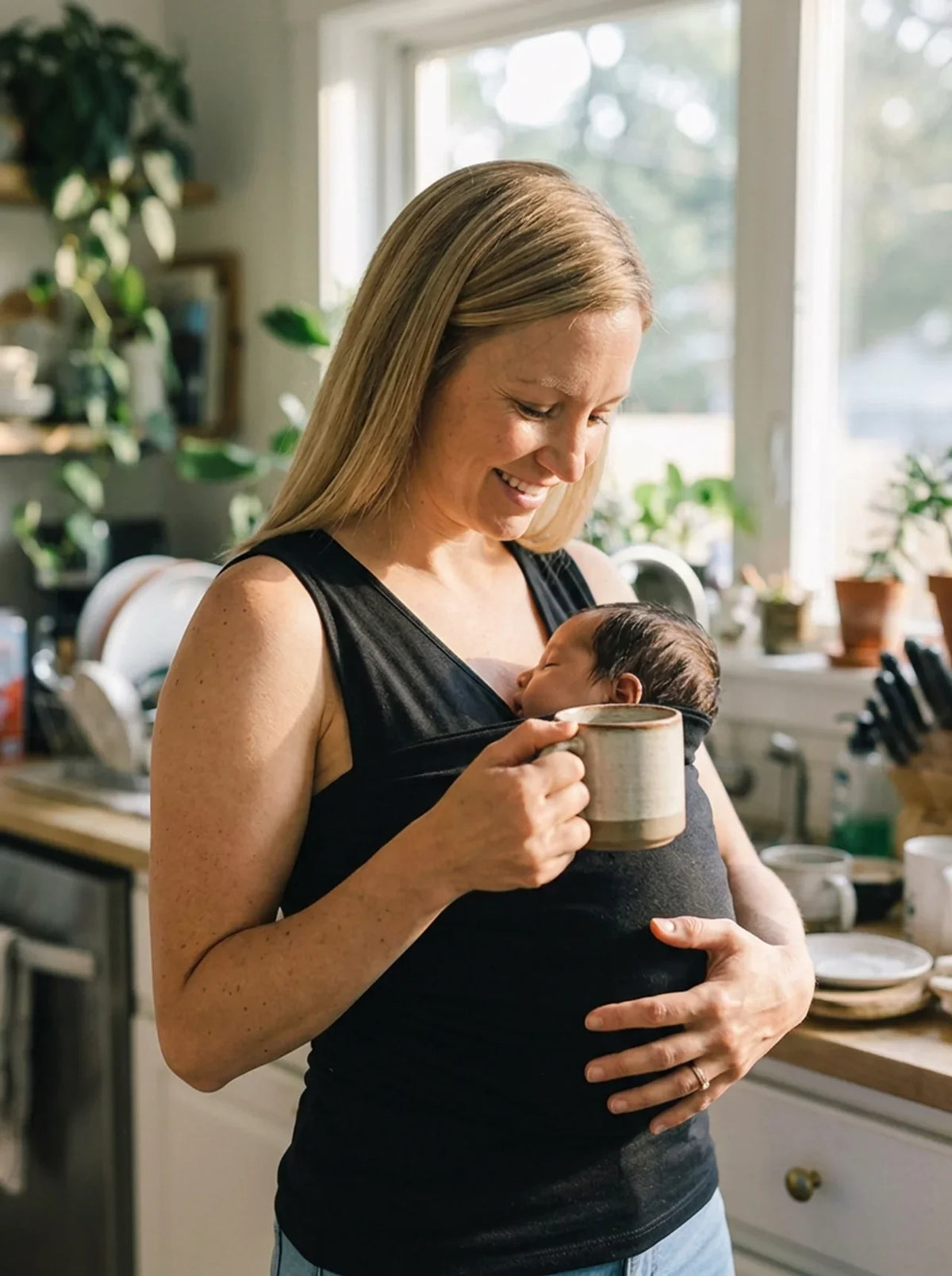Débardeur porte-bébé Hugaya porté par une mère, bébé installé contre elle, coloris noir